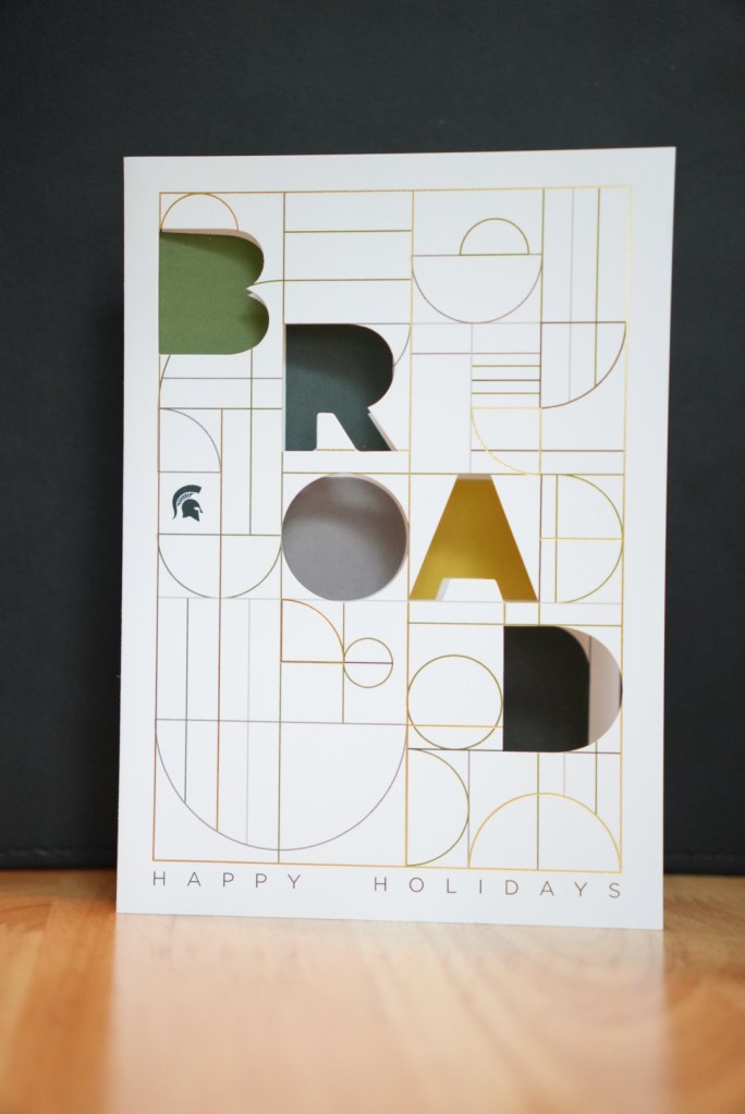Image of physical holiday card with "BROAD" spelled out in cutout lettering.